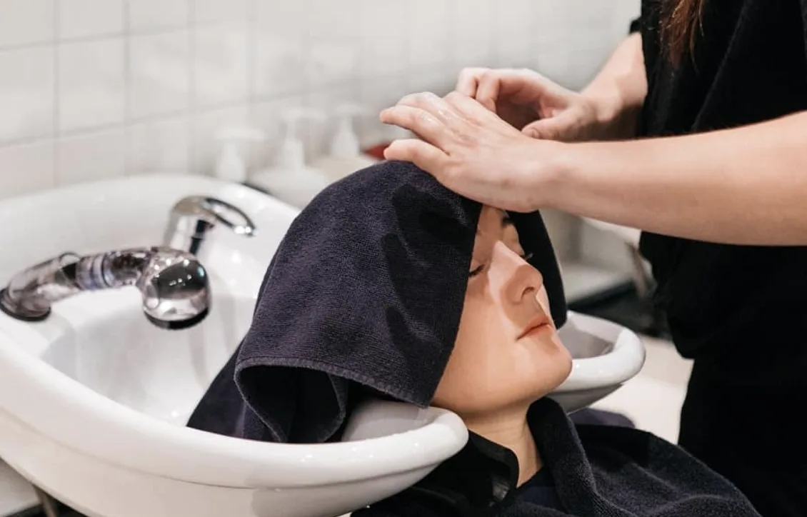 Stylist washing a client's hair at the basin inside Raw Edge salon